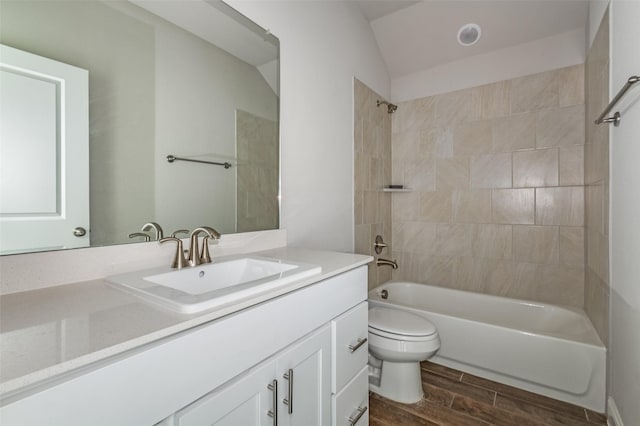 full bathroom featuring tiled shower / bath, lofted ceiling, toilet, and vanity