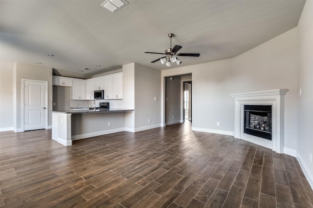 unfurnished living room with dark wood-type flooring and ceiling fan