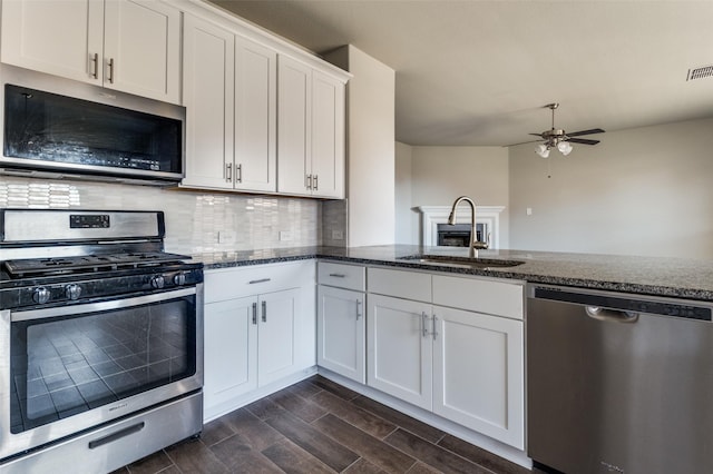 kitchen with white cabinetry, sink, backsplash, dark stone counters, and stainless steel appliances