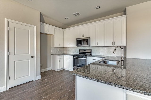 kitchen featuring sink, dark stone countertops, white cabinets, kitchen peninsula, and stainless steel appliances