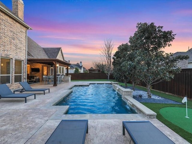 pool at dusk featuring a patio and pool water feature