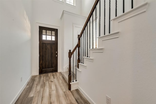 entrance foyer with a high ceiling, a wealth of natural light, and light wood-type flooring