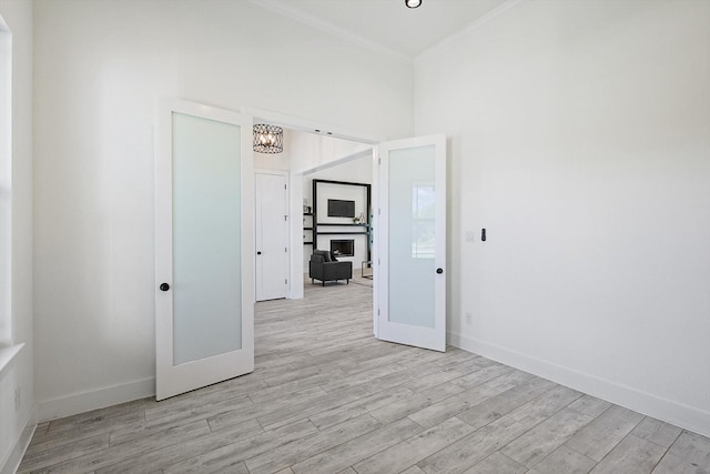 spare room featuring crown molding, light hardwood / wood-style floors, and a chandelier