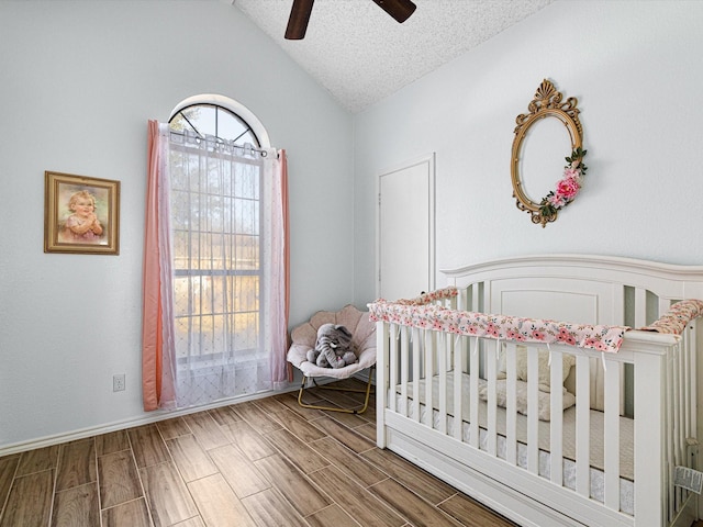 bedroom with a nursery area, lofted ceiling, a textured ceiling, and ceiling fan