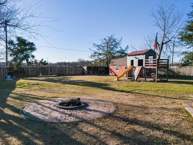 view of yard featuring an outdoor fire pit, a playground, and a shed