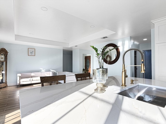 interior space with light stone counters, a tray ceiling, and sink