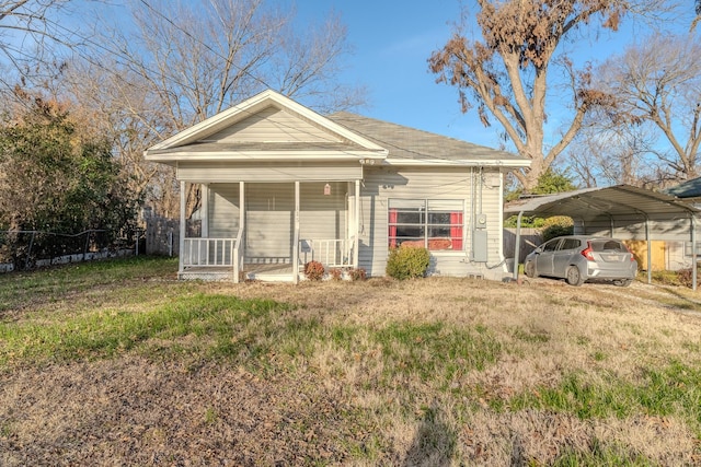 back of house with a carport, covered porch, and a lawn