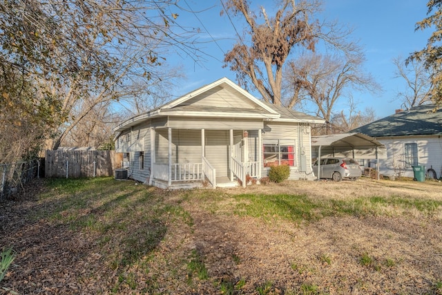 back of property with a carport, a yard, cooling unit, and covered porch