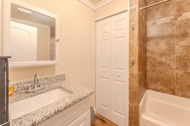 bathroom with tiled shower / bath, ornamental molding, and vanity