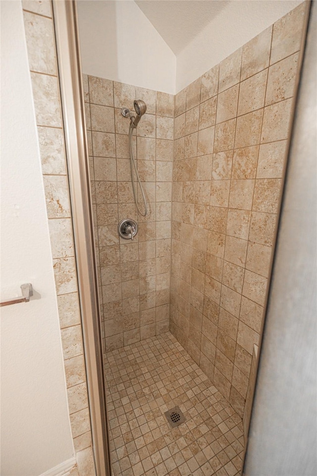 bathroom with a tile shower and vaulted ceiling