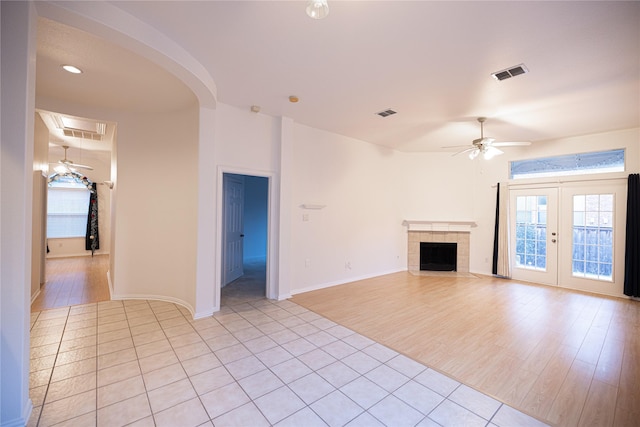 unfurnished living room featuring a fireplace, light hardwood / wood-style floors, and ceiling fan