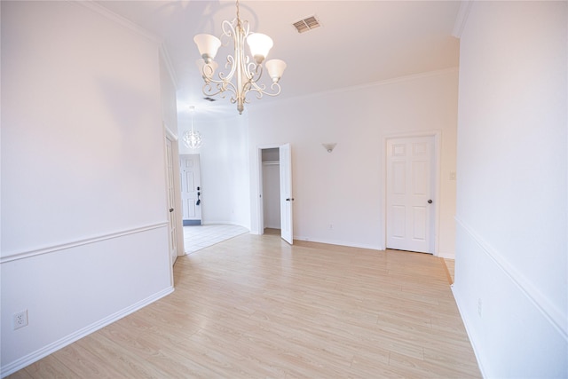 unfurnished room with an inviting chandelier, crown molding, and light hardwood / wood-style floors