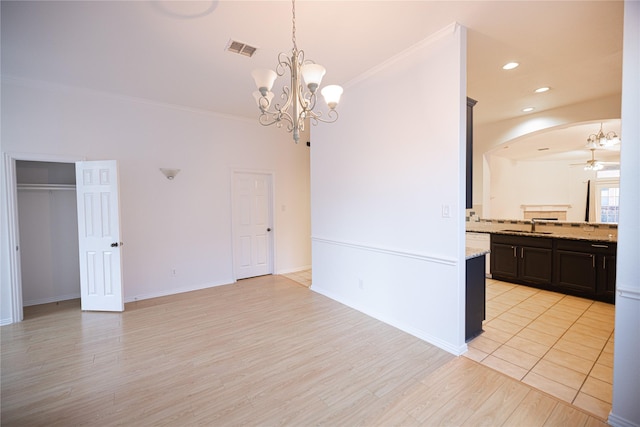 interior space with sink, crown molding, ceiling fan with notable chandelier, and light wood-type flooring