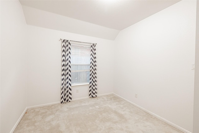 unfurnished room with lofted ceiling and light colored carpet