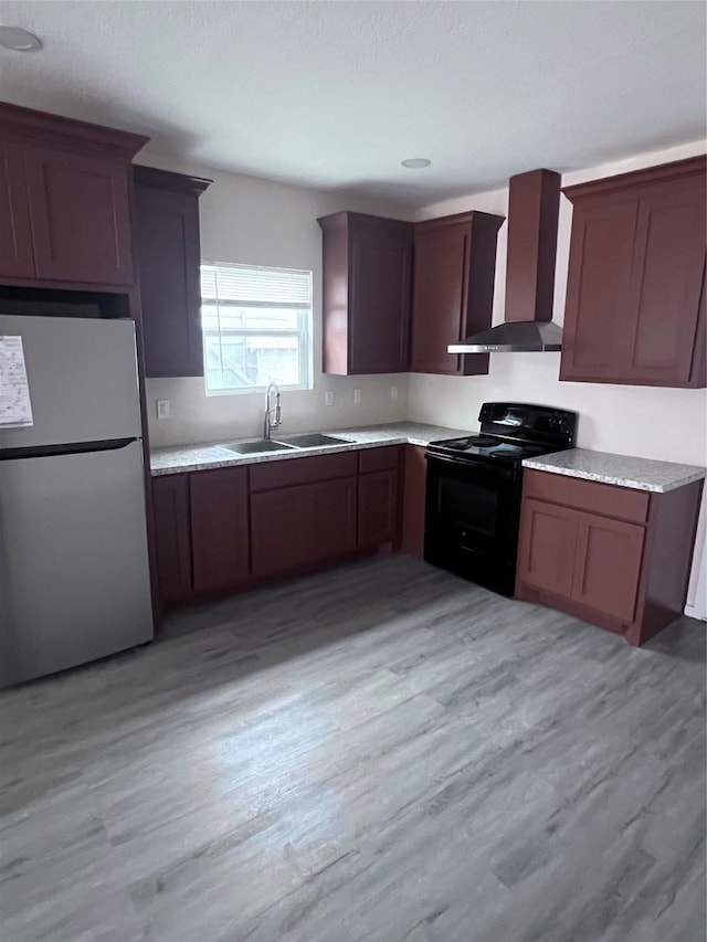 kitchen featuring sink, stainless steel fridge, light hardwood / wood-style floors, wall chimney range hood, and black / electric stove