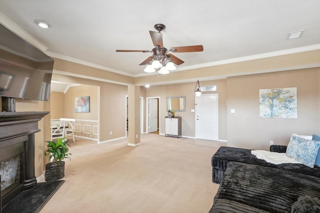 living room with a fireplace with raised hearth, crown molding, baseboards, ceiling fan, and light carpet