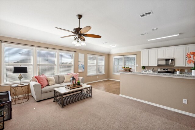 kitchen with a wealth of natural light, sink, white cabinets, stainless steel dishwasher, and light stone countertops