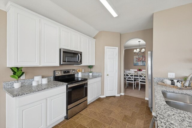 kitchen with sink, appliances with stainless steel finishes, white cabinetry, light stone counters, and kitchen peninsula