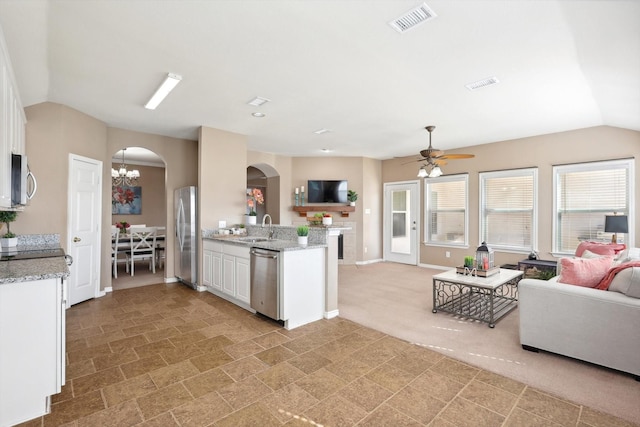 kitchen featuring visible vents, arched walkways, a sink, stainless steel appliances, and open floor plan