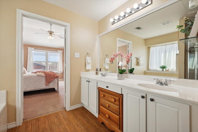 ensuite bathroom with double vanity, visible vents, wood finished floors, and a sink