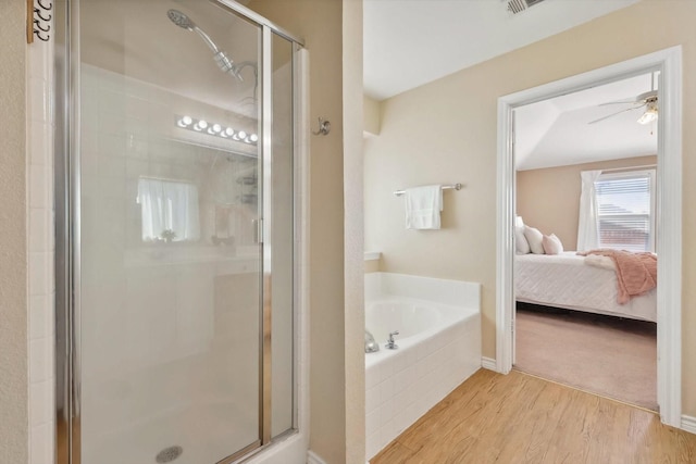 bathroom featuring a garden tub, a stall shower, wood finished floors, ensuite bath, and a ceiling fan