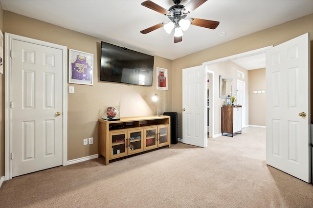 interior space featuring baseboards, light carpet, and a ceiling fan