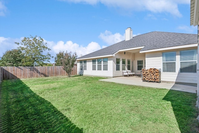 rear view of house with a patio, fence, roof with shingles, a chimney, and a lawn