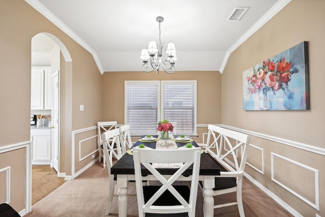 carpeted dining area featuring visible vents, a notable chandelier, ornamental molding, arched walkways, and vaulted ceiling