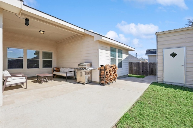 view of patio with an outbuilding, fence, and a grill