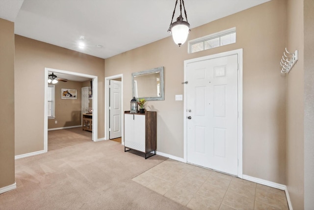 foyer with a wealth of natural light, baseboards, and light colored carpet