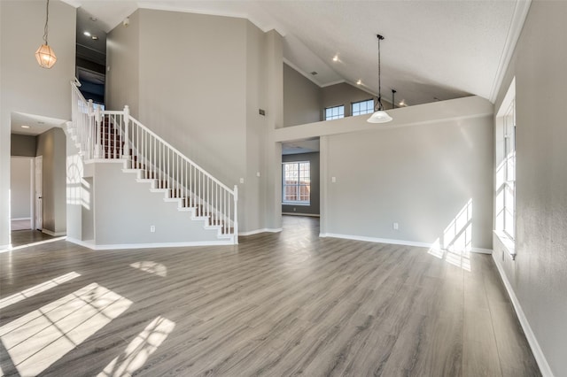 unfurnished living room with wood-type flooring and high vaulted ceiling