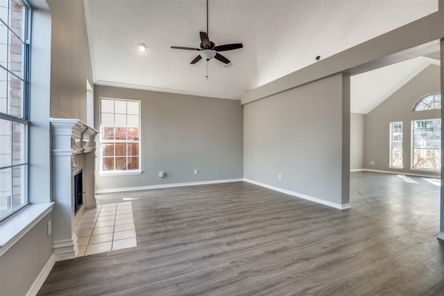 unfurnished living room with ceiling fan, vaulted ceiling, hardwood / wood-style floors, and a textured ceiling