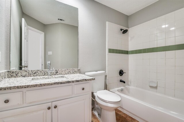 full bathroom with tiled shower / bath combo, vanity, toilet, tile patterned floors, and a textured ceiling