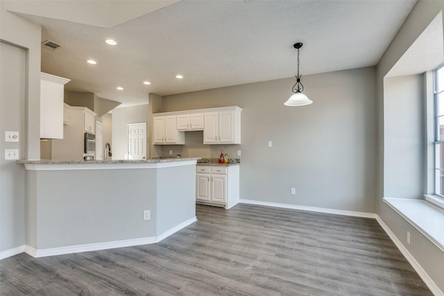 kitchen with a healthy amount of sunlight, light hardwood / wood-style flooring, white cabinets, and kitchen peninsula