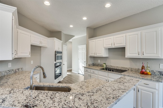 kitchen with white cabinetry, sink, and black electric cooktop