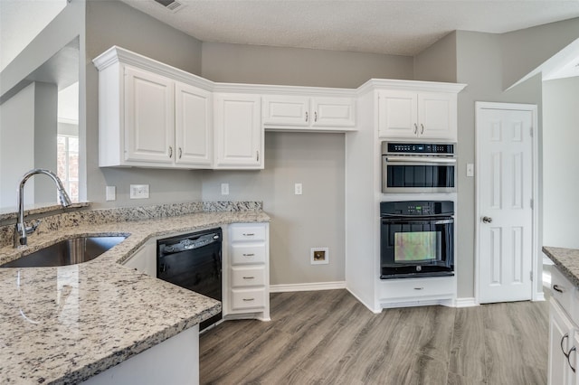 kitchen with sink, white cabinetry, multiple ovens, dishwasher, and light stone countertops