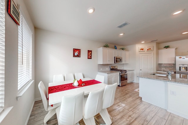 dining space with sink and light hardwood / wood-style floors