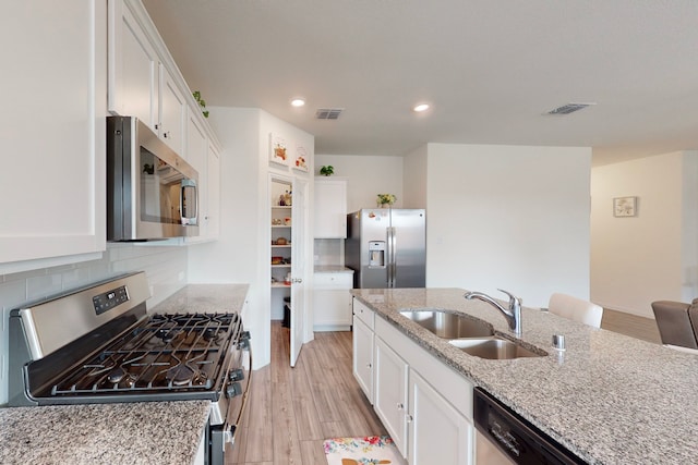 kitchen featuring white cabinetry, appliances with stainless steel finishes, sink, and light stone counters