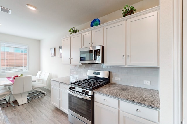 kitchen with appliances with stainless steel finishes, light stone countertops, and white cabinets