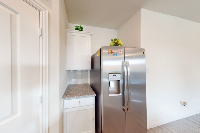 kitchen featuring light wood-type flooring, light stone countertops, white cabinets, and stainless steel refrigerator with ice dispenser