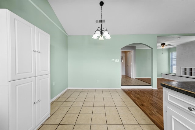 interior space with light tile patterned flooring and ceiling fan with notable chandelier