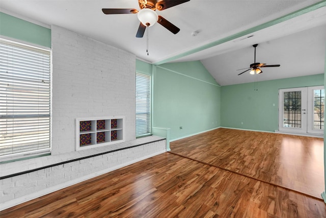 unfurnished living room featuring lofted ceiling, a brick fireplace, hardwood / wood-style flooring, and ceiling fan