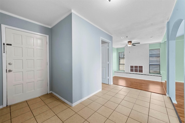 tiled entrance foyer with crown molding and ceiling fan