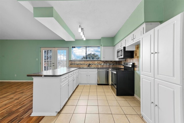 kitchen featuring french doors, appliances with stainless steel finishes, kitchen peninsula, decorative backsplash, and white cabinets