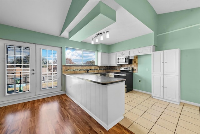 kitchen with sink, white cabinetry, kitchen peninsula, stainless steel appliances, and backsplash