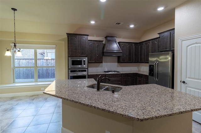 kitchen featuring premium range hood, an island with sink, sink, dark brown cabinetry, and stainless steel appliances