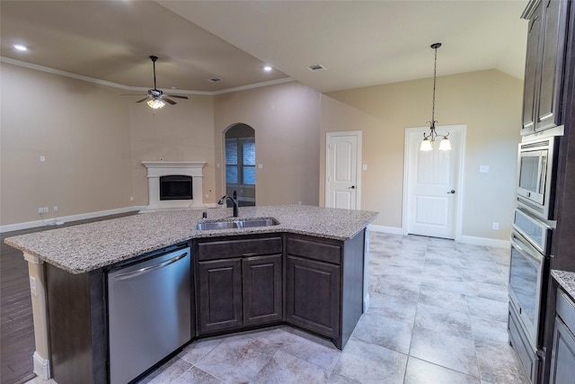 kitchen with appliances with stainless steel finishes, sink, dark brown cabinetry, light stone countertops, and a center island with sink