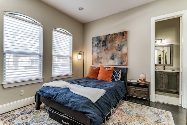 bedroom with dark hardwood / wood-style flooring, sink, and ensuite bath