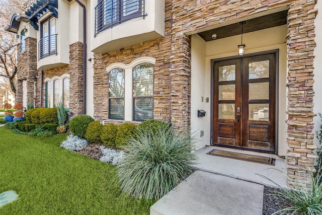 view of exterior entry featuring french doors and a lawn