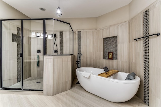 bathroom featuring shower with separate bathtub, tile walls, and tile patterned floors